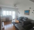 living room, black leather sofa, wooden table, wooden flooring, balcony, picture frames, window with curtains