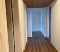 Empty hallway with wooden floor and white walls, wooden ceiling, doors on both sides