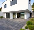 modern white house, large windows, garage, paved driveway, landscaped garden