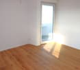 empty room with wooden floor, white walls, glass door to balcony