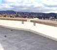 tiled rooftop, concrete parapets, view of the city, cloudy sky