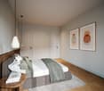 A well-lit, minimalist bedroom featuring a bed, a nightstand, artwork on the walls, and a rug beneath the bed.