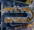 Building with green roof, multiple windows, parking area, surrounded by cars
