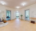 Entrance hall with wooden floor, white walls, large mirror, leather armchair, rug, wooden table, potted plant, decorative items