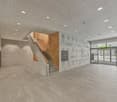 Open space, large tiles, wooden stairs, grey walls, bright lights