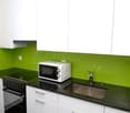 Modern kitchen with white cabinets, green backsplash, black granite countertop, built-in stove, microwave oven, and a sink