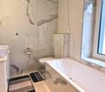 modern bathroom, white marble tiles, double sink vanity, separate toilet, bathtub, built-in toilet paper holder, double window