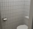 small bathroom, white tiled walls, white tiled floor, white toilet, silver toilet paper holder