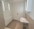 A bathroom with a sink, glass door, bathtub and white walls and flooring