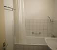 Tiled bathroom with a bathtub, shower curtain, and a sink