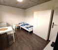 small bedroom with bed, white desk, white wardrobe, white chair, white refrigerator
