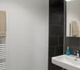 White sink, bottle of soap, mirror, black and white tiles, towel rack