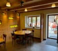 Cozy dining area with wooden walls, round wooden table, leather chairs, and large windows overlooking a balcony or terrace area.