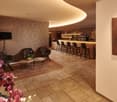 A modern reception area with a wooden bar counter, multiple brown leather armchairs, a wooden coffee table with flowers, a large painting, and floor lamps.