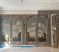 large room with decorative wall paintings, wooden pillars, checkered floor, unfinished ceiling