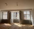 large room, wooden floor, white walls, large windows, radiators, sun rays