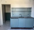 kitchen with sink, faucet, cabinets, shelves, and an open door