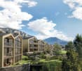 Modern apartment complex with multiple balconies, surrounded by greenery and mountains