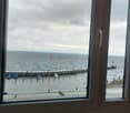 View of an ocean with pier, boats, a lighthouse, and a Swiss flag in the distance