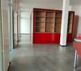long hall with red cabinet and shelves, grey tile floor, white ceiling, glass doors, no furniture