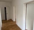 Empty room, wooden floor, white walls, open doors, electrical outlet