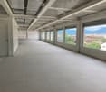 Empty room with white tiles, large windows, metal ceiling, and a door.