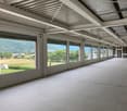 Empty room with large windows, tiled floor, metal ceiling, view of mountains and trees