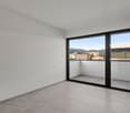 Spacious bedroom with large windows, sliding glass door leading to a balcony, and tile flooring.