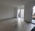 Spacious living room with large windows, sliding glass door leading to a balcony, and gray tile flooring.