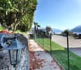 Stone pathway in garden with lamp, fence, green grass, mountain view