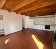 modern open kitchen, white cabinets, stainless steel appliances, red tile flooring, wooden ceiling, fireplace