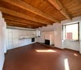 Open room with wooden ceiling, fireplace, kitchen area with sink and oven, large window