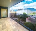 Terrace with glass railing, tiled flooring, view of the city and mountains