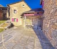 Old stone house with purple shutters, slate roof, pathway, exterior table, outdoor plants