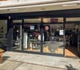 Clothing shop with glass walls, a small flowerbed at the entrance, and a digital sign board that says 'OPEN'