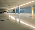 underground parking area, shiny clean floors, single car parked, multiple storage boxes