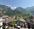 balcony, houses with tiled roofs, valley with mountains, green valley in between