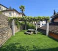private garden, grassy lawn, stone walls, pergola, table, benches, grapevines