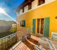 yellow exterior, green shutters, balcony with table and chairs, potted plants, sunny view