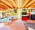 Dining room with wooden ceiling, dining table, chairs, paintings on the wall, TV, rug, cabinet, and shelves