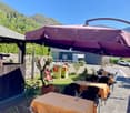 Outdoor seating area with tables, chairs, large purple umbrella, and views of the mountain in the background
