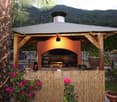 wooden gazebo with a chimney, outdoor fireplace, greenery, flowers, and a beautiful view