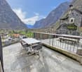 Stone floor, metal railing, table and chairs, bench, mountains in the background