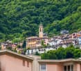 Mountain town, several multi-story buildings, one with a clock tower, lots of greenery