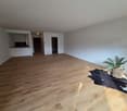 empty room, wooden floor, white walls, plant, rug, kitchen area, door, power outlets