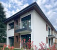 Modern 2 story house, white exterior, brown wooden accents, glass windows, balconies, green lawn