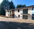 Modern design, 2-story house, white exterior, glass windows, balconies with railings, fenced entrance.