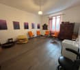 Wooden floor, white walls, orange chairs, sink, cabinets, artworks