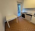 white table, white cabinets, tiled floor, open door leading to oven, sink with faucet, sliding glass door