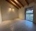 empty room, wooden floor, white walls, large window, ceiling with wooden beams and integrated lighting, view of trees